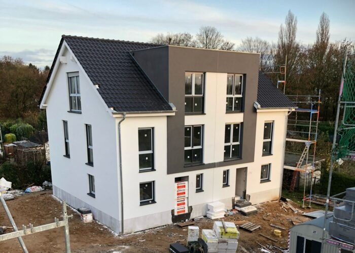 Foto 1 Ein fast fertiges Haus in weiß mit grauen Dächern.